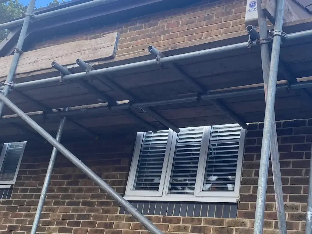 Scaffolding on the side of a brick house for roof repairs or installation