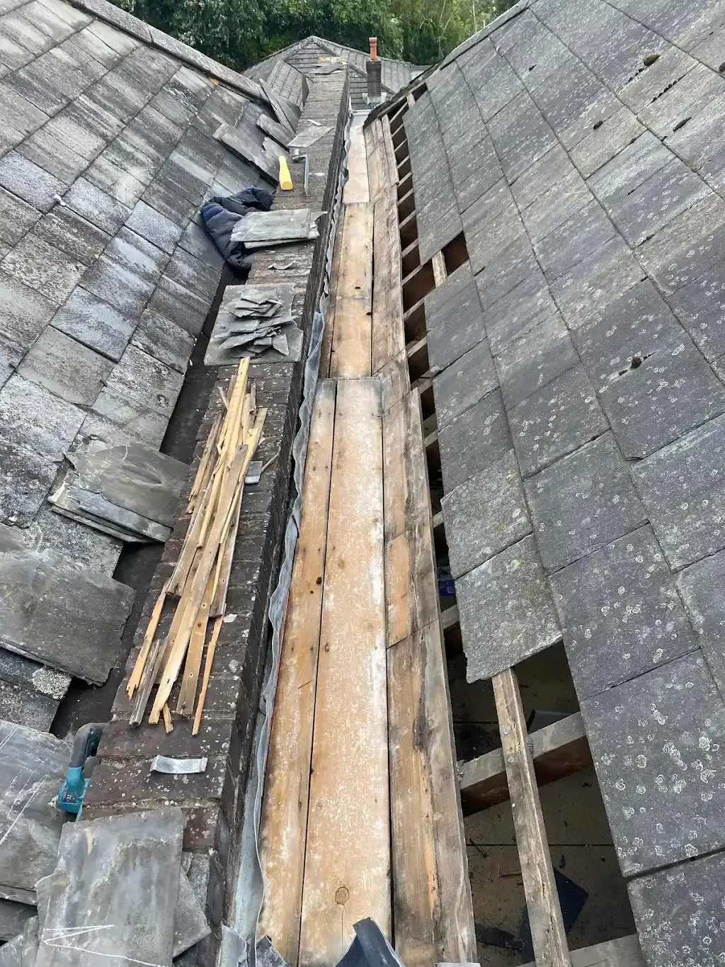 Roof repair in progress with tiles and battens removed, exposing the timber framework.